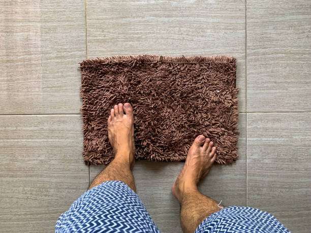 a man's feet on a brown bath mat