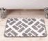 Grey geometric patterned bath mat near a white bathtub.