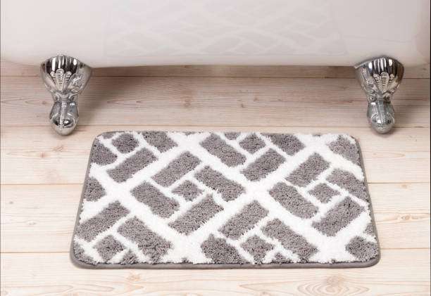 Grey geometric patterned bath mat near a white bathtub.