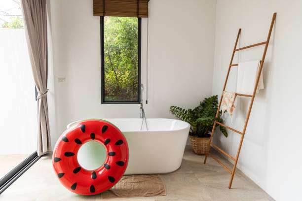 Modern bathroom with white tub, watermelon float, and a brown bath mat on the tile floor.