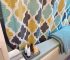 Colorful shower curtain, folded blue towel, and small toiletries with a soft bath mat nearby.