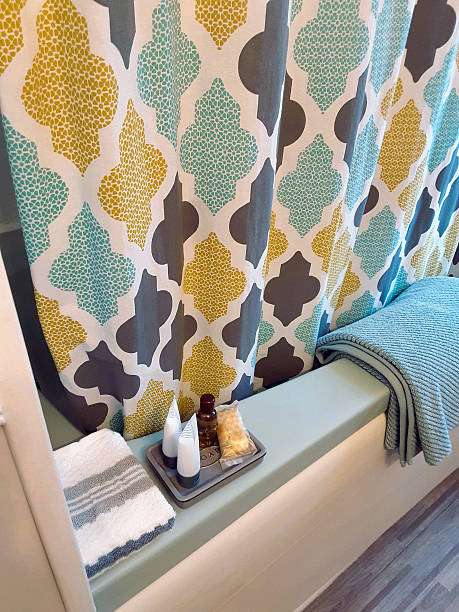 Colorful shower curtain, folded blue towel, and small toiletries with a soft bath mat nearby.