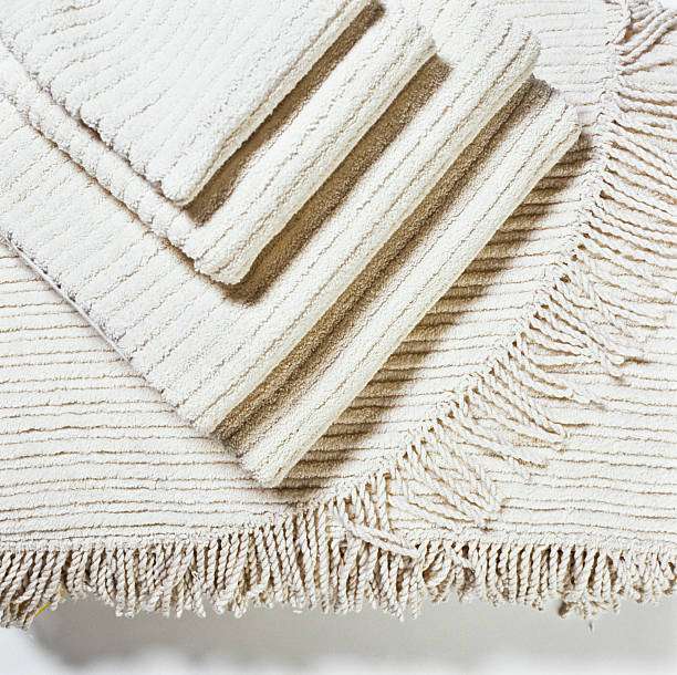 Textured cream bath mat with fringe detail.