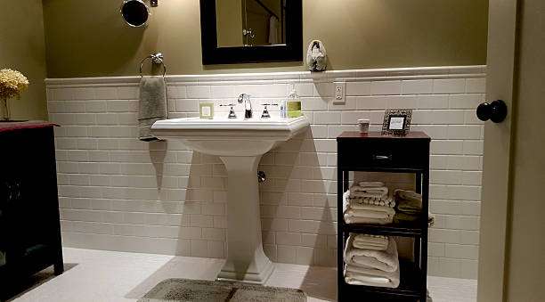 White subway tile bathroom with pedestal sink and bath mat.