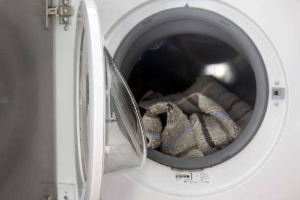 Washing machine with a patterned item inside, ready to clean a dirty bath mat.
