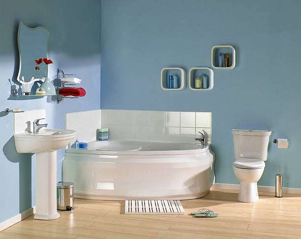 Blue bathroom features a corner tub, sink, toilet, and a striped bath mat on the floor.