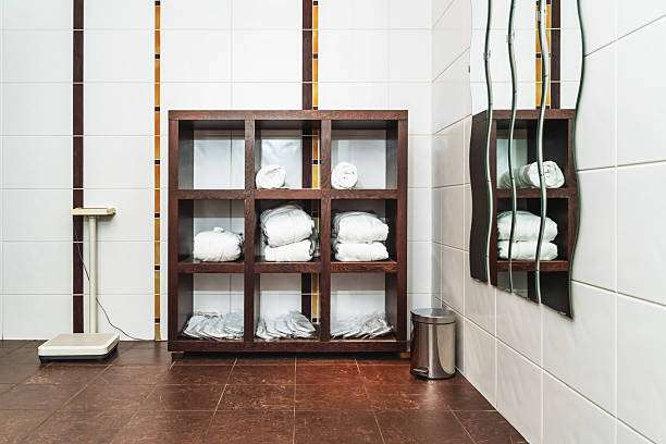 Clean, tiled bathroom with towel shelves and scale, perfect for adding a stylish bath mat.