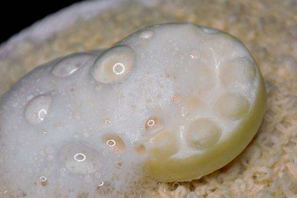 Soapy bar with water droplets resting on a textured surface, similar to a bath mat.
