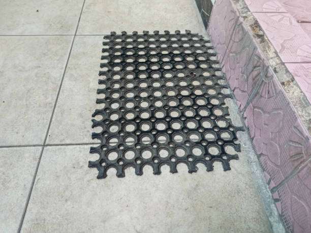 Black rubber honeycomb bath mat on tiled floor.
