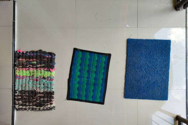 Three bath mats, one blue, one striped, one woven.