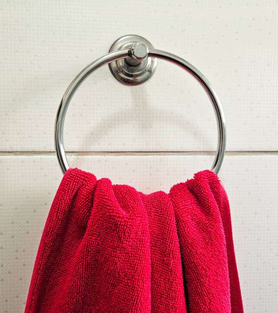 Red towel hanging on a towel ring, not a bath mat.