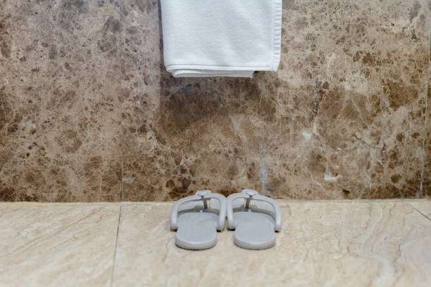 Flip-flops and towel near a marble wall, no bath mat visible.