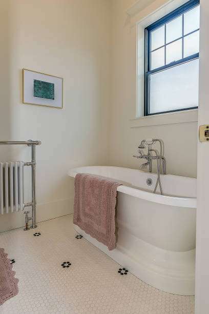Elegant bathroom featuring a freestanding tub and a soft, patterned bath mat on hexagon tiles.