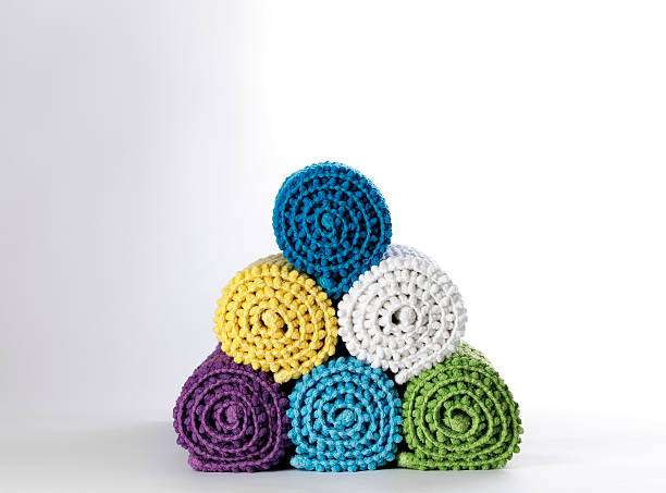 A pyramid stack of colorful, rolled-up textured bath mats in various vibrant hues.