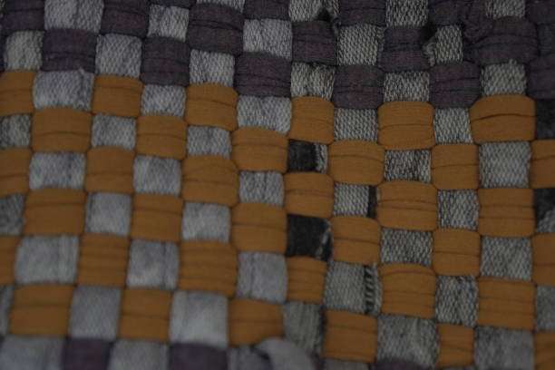Close up of a woven bath mat with grey and tan.